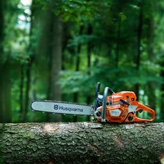 an orange chainsaw sitting on top of a tree in the woods