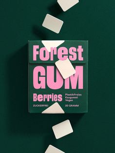 a box of gum sitting on top of a green table next to white cubes