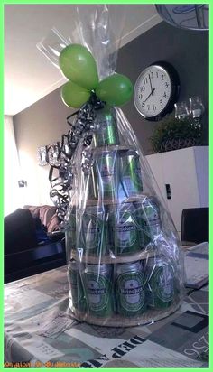 a table topped with lots of green beer bottles next to a wall clock and balloons