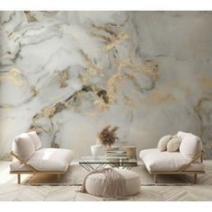 two chairs and a table in front of a marble wall with gold foiling on it