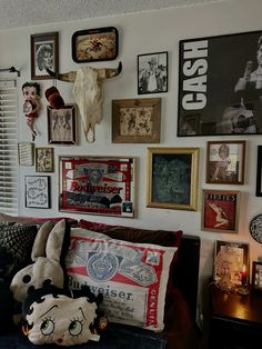 a living room filled with lots of framed pictures and stuffed animals on the wall next to a couch