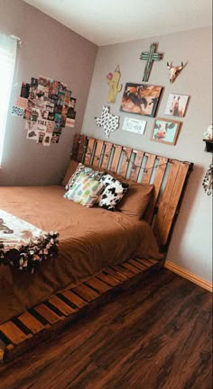 a bed sitting on top of a hard wood floor next to a wall covered in pictures