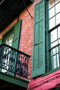 an old brick building with green shutters and balconies