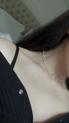 a close up of a woman wearing a black shirt and diamond necklace on her neck