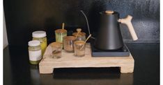 a wooden tray topped with different types of condiments next to a tea pot