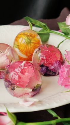 three pieces of fruit sitting on top of a white plate next to pink flowers and green leaves