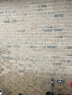 a bathroom with a toilet, sink and brick wall