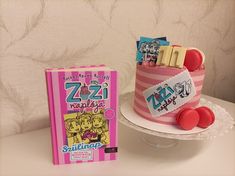 a pink and white cake sitting on top of a table next to a book