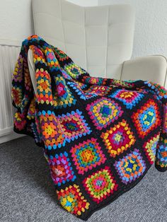 a colorful crocheted blanket sitting on top of a white chair