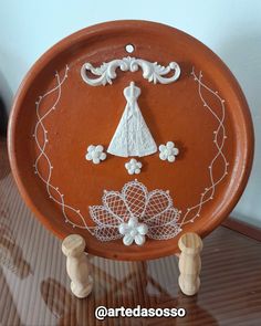 an orange plate with white decorations on it and two wooden pegs in front of it