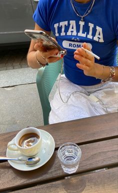 a woman sitting at a wooden table with a cup of coffee in front of her