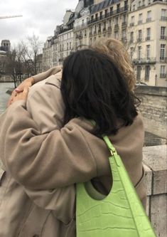 a woman with her back to the camera carrying a lime green purse over her shoulder