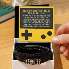 a person is holding up a bracelet in a box that says, gear up and get ready for level 1