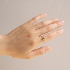 a woman's hand with a gold ring on top of her left hand and a white wall in the background