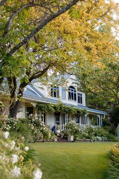 a white house surrounded by trees and flowers