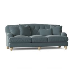 a blue couch with several pillows on it's back and legs, in front of a white background