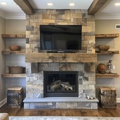 a living room with a fire place and shelves on either side of the fireplace that has a flat screen tv above it