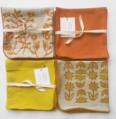 four napkins with tags tied to them in different colors and designs on white background