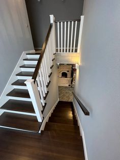 a staircase leading up to a fire place in a house with wood floors and white railings