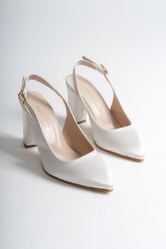 a pair of white high heeled shoes sitting on top of a white table next to each other