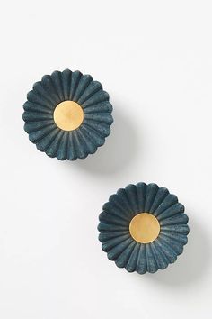 two blue and gold flower shaped dishes on a white surface with one yellow disc in the middle