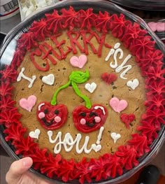 someone is holding up a cake decorated with hearts and cherries on the bottom, which reads i love you