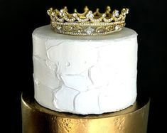 a three tiered cake with a crown on top and gold trim around the edges