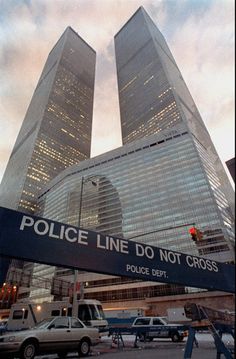 two very tall buildings in the middle of a busy street with cars parked below them