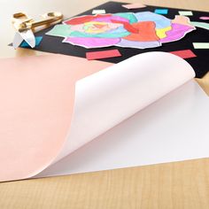 an open piece of paper sitting on top of a wooden table next to scissors and other crafting supplies