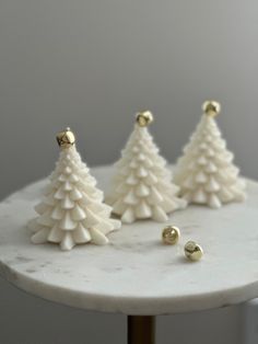 three white christmas trees sitting on top of a marble table