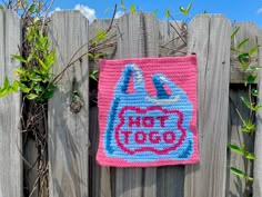 a crocheted bag hanging on a wooden fence