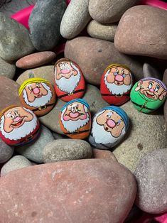 several rocks with cartoon characters painted on them sitting next to some pink and gray rocks