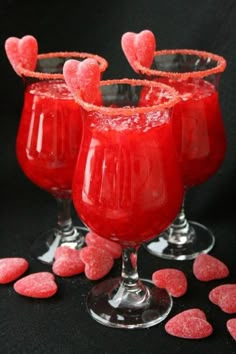 three glasses filled with red liquid and hearts