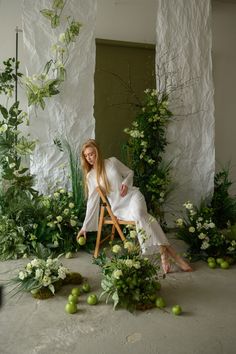 a woman sitting in a chair surrounded by plants