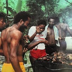 several men standing around grilling meat on an open fire