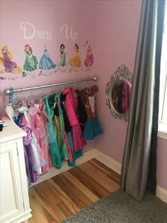 there is a closet with princess clothes hanging on the wall and a mirror next to it