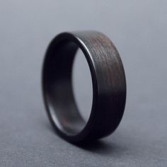 a black ring with wood in it on a gray surface, showing the inside of the ring