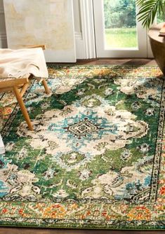 a green rug with an ornate design on the floor in front of a chair and potted plant