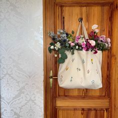 a white bag with flowers hanging from it's side on a wooden door handle