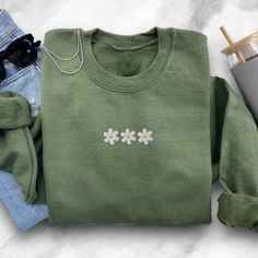 "Elevate your style with our \"Daisy Flower Embroidered Sweatshirt.\" This charming sweatshirt is a celebration of daisy flowers, featuring beautifully embroidered blossoms that add a touch of natural elegance to your wardrobe. 🌼 Daisy Delight: Our sweatshirt showcases intricately embroidered daisy flowers, allowing you to embrace the beauty of nature wherever you go. It's the perfect blend of fashion and comfort for daisy lovers. 💐 Versatile Chic: Whether you're off for a casual day out, enjoying a cozy evening at home, or simply want to add a touch of floral elegance to your attire, this sweatshirt effortlessly enhances your style. 🍃 Unmatched Comfort: Crafted from soft and high-quality materials, our crewneck sweatshirt offers cozy warmth and comfort. It's the perfect choice for stay Cute Green Sweatshirt For Spring, Green Crew Neck Sweatshirt With Floral Embroidery, Crochet Shoes Pattern, Crochet Bandana, Floral Sweatshirt, Daisy Flowers, Crochet Shoes, Sweater Gift, Embroidered Clothes