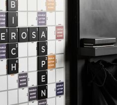 a person standing in front of a wall with scrabble tiles on it and the words across them