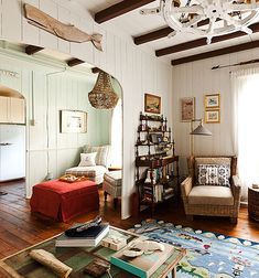 a living room filled with furniture and a chandelier hanging from the ceiling in front of a window