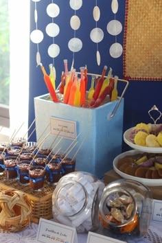 an assortment of desserts and pastries are displayed on a table in front of a blue wall