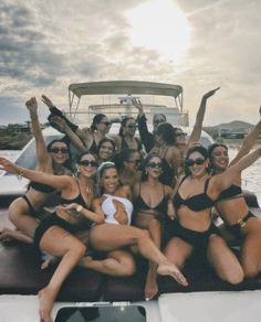 a group of women in bikinis on a boat posing for the camera with their arms up