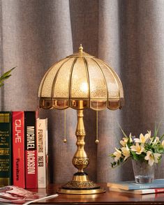 a lamp sitting on top of a wooden table next to a vase filled with flowers