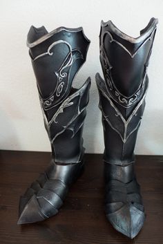 a pair of black boots sitting on top of a wooden table