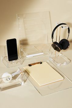 a clear desk with headphones, notepad and cell phone on it's stand