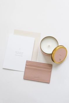 a candle, card holder and envelope on a white surface with a pink leather wallet