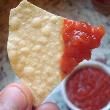 a person holding up a piece of cheese and salsa