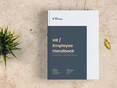 an employee's workbook next to a potted plant on a marble surface